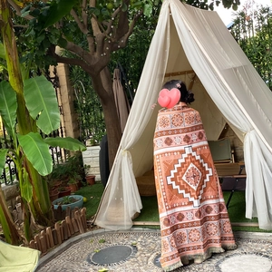 Bohemian geometric knit outdoor camping blanket with fringes in a cozy garden setting