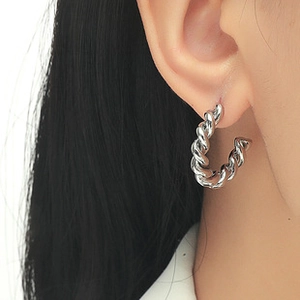 Close-up of twisted silver hoop earrings showing the polished spiral metal texture