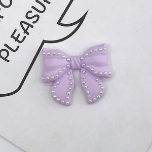 Close-up of purple resin bow DIY accessory with white faux pearl trim for phone cases