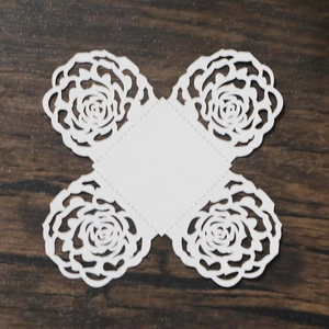 Flat lay of unassembled white laser-cut rose hollow candy box template on wood texture