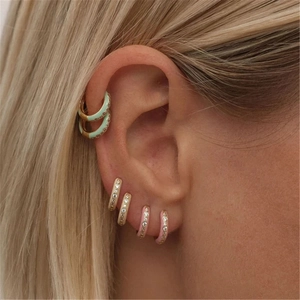 Detail of colorful gold-plated hoop earrings with small white zircons on a model's ear