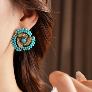 Close-up of vintage flower earrings with turquoise beads and crystals on model