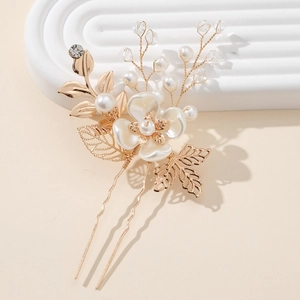 Elegant gold leaf and pearl bridal hair pin featuring crystal accents on a textured tray
