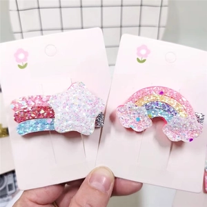 Detail of glitter rainbow and star hair clips for kids on pink cards in a close-up view