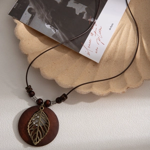 Vintage long woven rope necklace with wood beads and bronze leaf pendant in boho style