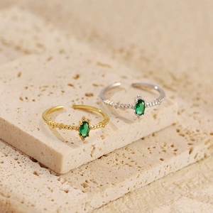 Close-up of gold and silver adjustable rings with oval green zircon and side crystals