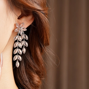 Close-up of silver flower tassel earrings with crystals worn by a model in soft lighting