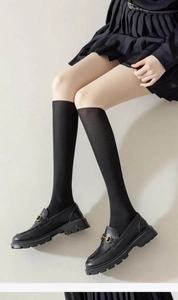 Texture détaillée de chaussettes hautes noires avec mocassins à plateforme et boucle dorée