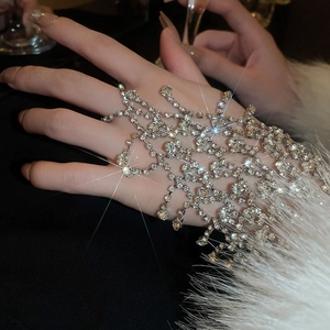 Detail of a sparkling rhinestone tassel hand harness ring bracelet on model with fur cuff