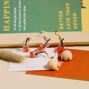 Detail shot of creative strawberry cold drink bottle earrings with gold and silver hooks