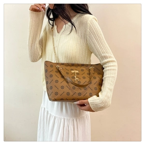 Detail of a brown tote bag with repeating VISHINE patterns and a gold deer pendant charm