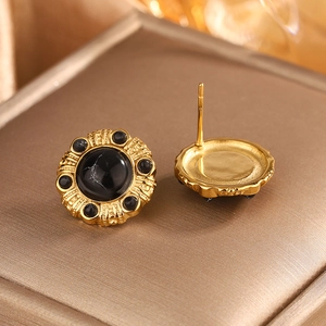 Close-up of vintage 18K gold plated earrings with radiating texture and black marble stones