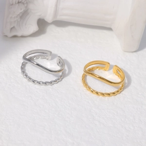 Detail of double-layer stainless steel ring with twisted rope and smooth gold textures