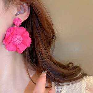 Gros plan sur d'élégantes boucles d'oreilles fleurs en tissu rouge rose avec spirale