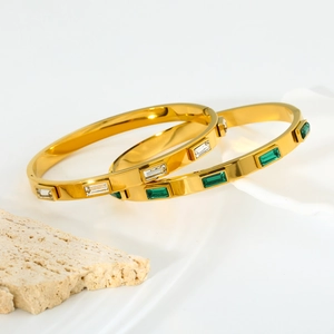 Detail of gold-plated stainless steel bracelets with clear and emerald zirconia stones