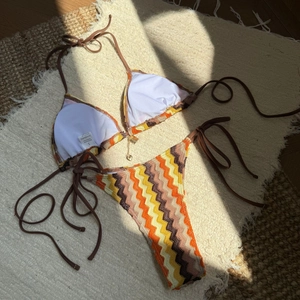 Close-up of a striped bikini featuring a gold heart pendant and 82% polyester material