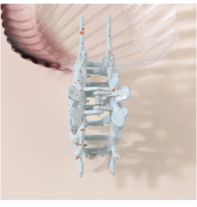 Detail of light blue conch hair claw with orange and purple speckles showing inner spring