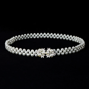 Macro detail of elastic multi-row pearl waist belt with silver floral buckle design