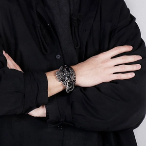 Detailed view of wide skull engraved stainless steel cuff bracelet on male model wrist
