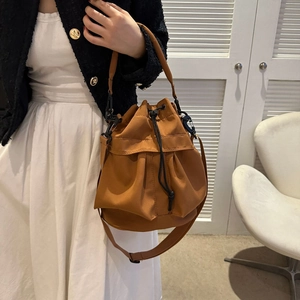 Sac seau en nylon caramel avec cordon de serrage porté par un mannequin pour un look décontracté