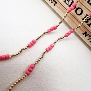 Detail of pink resin beads and gold micro spacer beads on a multi-purpose jewelry chain