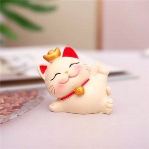 Macro shot of reclining Lucky Cat resin ornament with gold ingot and red bow detailing