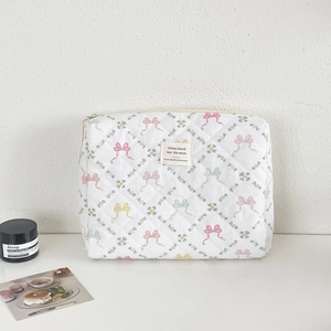 Détail de la trousse à maquillage matelassée avec imprimés nœuds et étiquette tissée
