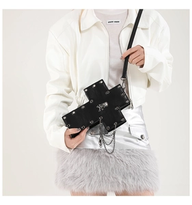 Gothic cross crossbody bag with metal rivets and chains shown on a fashion model