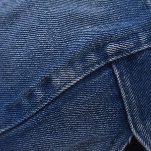 Gros plan du tissu en denim délavé bleu foncé avec texture sergé de coton et surpiqûres