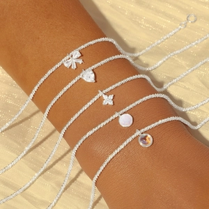 Detailed view of S925 silver bracelets featuring bow, heart, and opal pendants on wrist