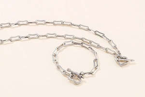 Close-up of silver stainless steel paperclip chain necklace and heart OT buckle set