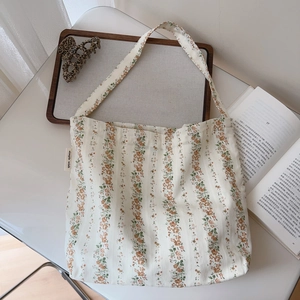 Detail showing the floral canvas shoulder bag with a 'simple wish' tag and cotton fabric