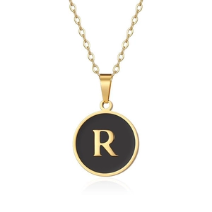Dettaglio della collana dorata con pendente tondo in smalto nero e lettera R