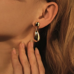 Polished 18K gold waterdrop earrings displayed on a model with mirror finish