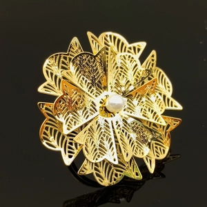 Macro shot of large golden hollow flower ring with a center white pearl on black background
