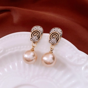 Detailed close-up of vintage gold pearl earrings with crystal inlay on an embossed plate