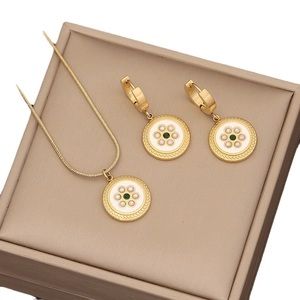 Golden necklace and earrings set with white enamel and green stones in a beige gift box