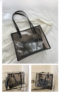 Detail view of large black transparent PVC tote bag with FASHION logo and inner pouch