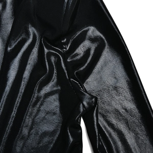 Détail du tissu en maille enduit noir avec texture brillante et effets de fronces