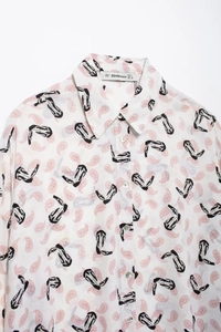 Close-up of vintage paisley and cowboy boot print on a white button-down shirt collar