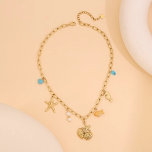 Détail du collier océan doré avec pendentifs étoile de mer, coquillage et cœur bleu