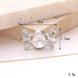 Macro detail of silver candy-shaped shoe charm with sparkling gemstone and 2cm size specs