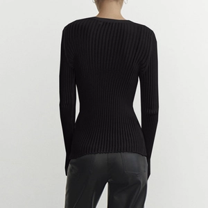 Close-up of black ribbed knit long sleeve top showing tight fit and textured fabric