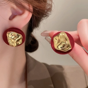 Detail of red and gold vintage earrings featuring a textured heart design on a model