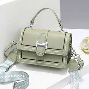 Light green faux leather handbag with contrast stitching and jacquard strap on white stand