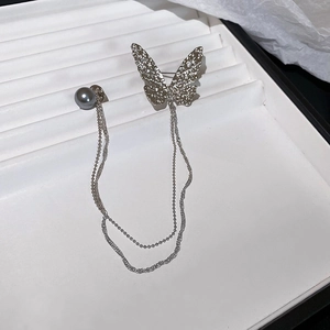 Detail of silver butterfly brooch with hammered metal finish, pearl, and double bead chains