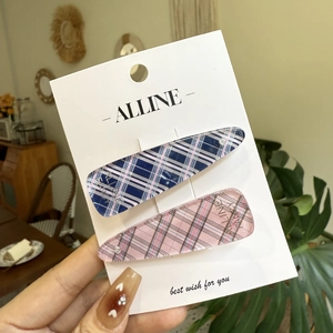 Close-up of pink and blue plaid checkered hair clips on a branded display card
