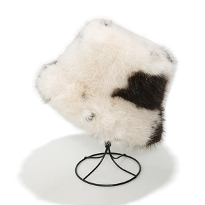 Detail of soft faux fur bucket hat with cow print pattern on a metal display stand
