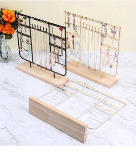 Detail of jewelry organizer with gold metal hooks and solid wood base on marble