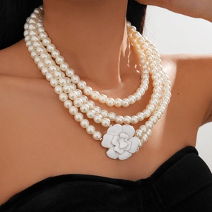 Close-up of layered faux pearl necklace featuring a white camellia flower pendant